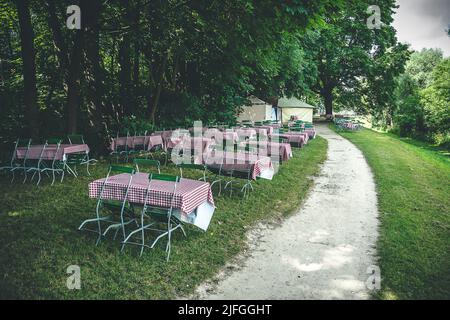 Leere Tische in einem Biergarten an der Donau in Regensburg in Bayern Stockfoto