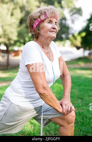 Ältere Frau, die sich im Park aufwärmt Stockfoto