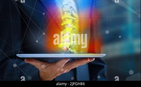 Arzt beobachtet eine Röntgenaufnahme von Hüfte und Wirbelsäule auf Rückenschmerzen auf einem digitalen Tablet. Stockfoto