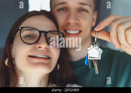 Konzentrieren Sie sich auf Schlüssel, die von begeisterten jungen Ehepartnern Hausbesitzer gehalten werden. Glücklich verheiratetes Familienpaar feiert Umzug in neues Haus zu Hause , demonstriert Schlüssel, standi Stockfoto