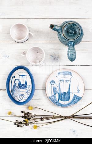 Tassen, Teekannen und bemalte Teller liegen flach Stockfoto