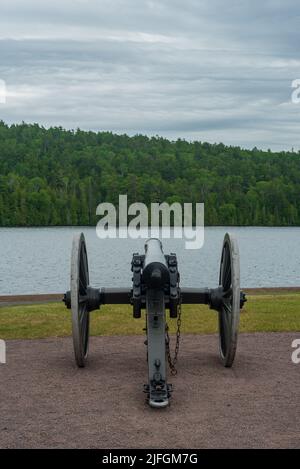 Historische schwarze Pulverkanone, die über einer Küstenlinie wacht Stockfoto