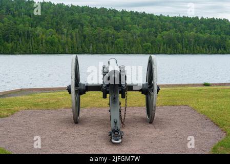 Historische schwarze Pulverkanone, die über einer Küstenlinie wacht Stockfoto