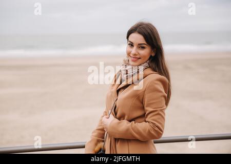 Stilvolle Dame mit Make-up in schönen Mantel stehen entlang der Nordsee. Frau lächelt Stockfoto