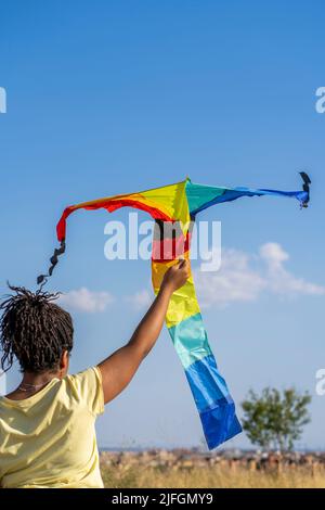 Afroamerikanische Frau, die einen bunten Drachen fliegt Stockfoto