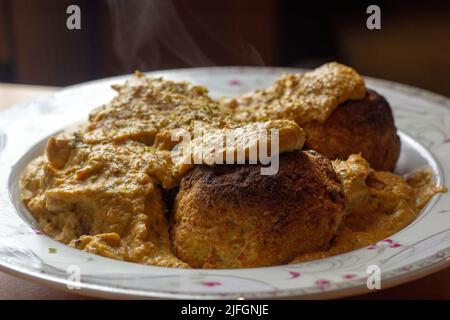 Gebackene Malai Kofta mit reichhaltiger, dicker Sauce auf einem weißen Teller. Es ist indische Küche Gericht mit Kartoffeln und Paneer Käse in der Regel frittierte Kugeln in Zwiebeln zu Stockfoto