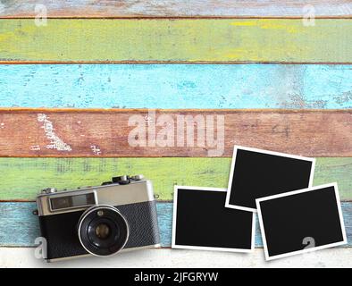 Vintage-Kamera und alte leere Fotorahmen auf Schreibtisch oder Holz texturierten Hintergrund. Vintage- und Retro-Stil mit Geschäftsreisekonzept. Draufsicht Stockfoto