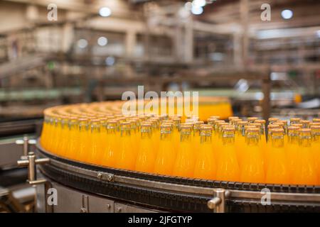 Innenausstattung der Getränkefabrik. Förderband mit Flaschen für Saft oder Wasser. Stockfoto