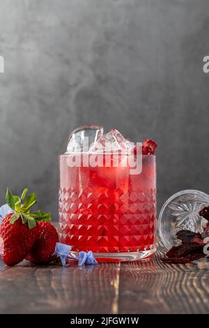 Eisgekühlter Erdbeertee mit Scheiben getrockneter Erdbeeren auf Holztisch Stockfoto