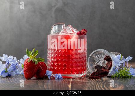 Eisgekühlter Erdbeertee mit Scheiben getrockneter Erdbeeren auf Holztisch Stockfoto