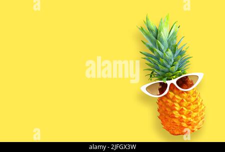 Sommerhintergrund. Lustige Ananas in Sonnenbrillen auf gelbem Hintergrund. Stockfoto