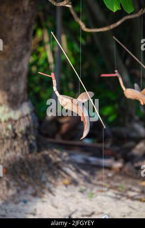 Spielzeugvögel aus Kokosnussschalen für Touristen an einem tropischen Strand in Thailand, aus nächster Nähe Stockfoto