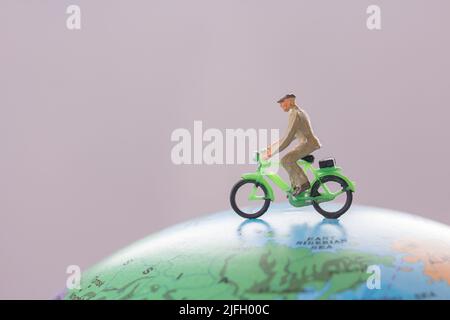 Miniatur Menschen - Figur businessmans Radfahren auf Mini-Kugel-Modell mit verschwommenem Hintergrund. Business Finance und Reisekonzept. Stockfoto