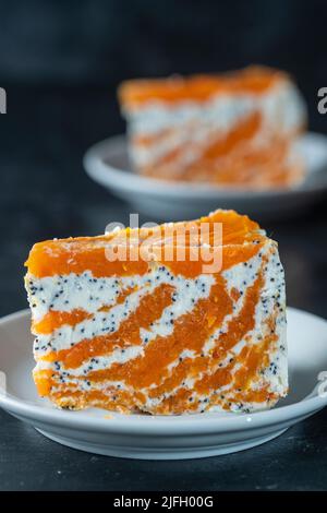 Stück zarte Karotten-Quark-Torte mit Mohn, Honig und Orangensaft auf dem Teller, Nahaufnahme. Kuchen ohne Backen Stockfoto