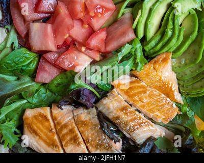 Nahaufnahme von gesunden Speisen zum Mitnehmen, Lachs, Tomaten, Avocado, Salat. Gesunder Lebensstil, Essen am Arbeitsplatz Stockfoto