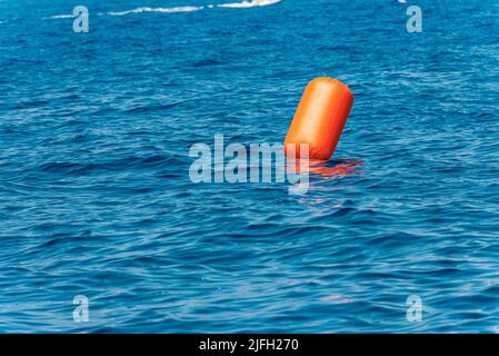 Eine große aufblasbare Signalboje in Orange, die im blauen Mittelmeer, im Golf von La Spezia, Ligurien, Italien, Europa schwimmt. Stockfoto