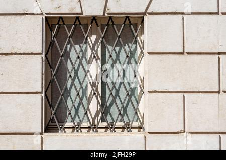 Nahaufnahme eines Fensters mit schmiedeeisernen Sicherheitsstangen an einer weißen Marmorwand. Trentino-Südtirol, Italien, Europa. Stockfoto