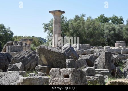 Archäologische Ausgrabungen im antiken Olympia, Peloponnes. Landschaft mit alten Steinen (Säulen), Bäumen und Felsen. Olympia / Griechenland - 15. Juli 2020 Stockfoto