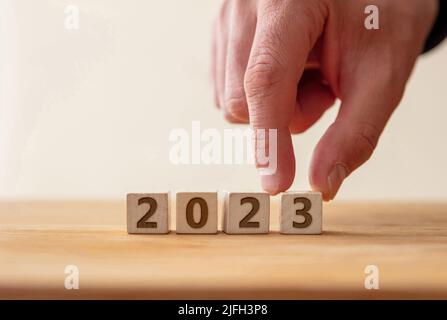 2023 Happy New Year Celebration Konzept. 2023 Zahl auf Holzwürfel mit Finger bis zur Ziffer 3. Neuer Plan, Geschäft, Karriere, Ziel, Erfolg. Begrüßung Stockfoto