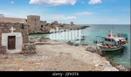 Griechenland. Gerolimenas Dorf, Mani Laconia, Peloponnes. Kleines Pel, Fischerboot in ruhigem Meer, Ruine Steingebäude auf felsigem Land, Stockfoto