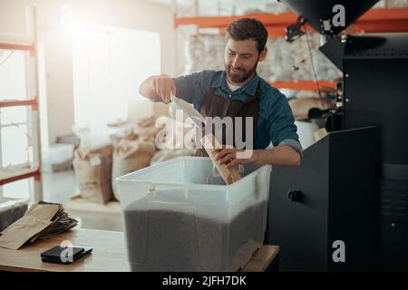 Uniformierte Arbeiter verpackt geröstete Kaffeebohnen in Verpackungen zum Verkauf Stockfoto