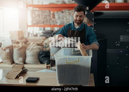 Der Geschäftsinhaber packt geröstete Kaffeebohnen zum Verkauf in Pakete Stockfoto