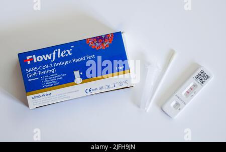 Flowflex Covid-19 Schnelltest, Antigentest, Hometest neben dem Tupfer mit positivem (zwei Linien) Ergebnis auf Testkarte. Stockfoto