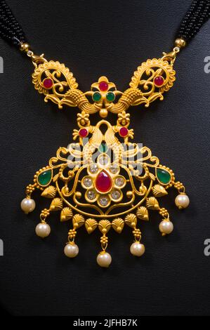 Closeup Temple Gold Halskette ( Mangalsutra) mit schwarzen kleinen Perlen auf schwarzem Hintergrund Stockfoto