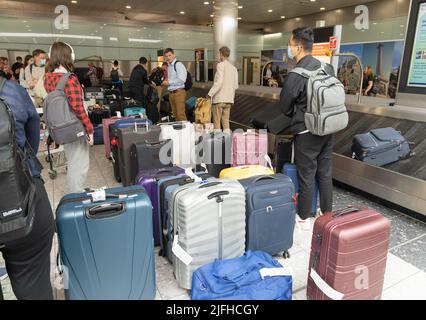 Verspätungen am Flughafen Heathrow; Personen, die aufgrund von Störungen durch Gepäckstapel suchen, Gepäckabholung am Terminal 3, London Heathrow UK Stockfoto