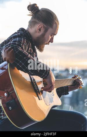 Ein Mann mit Bart spielt die akustische Gitarre. Stockfoto