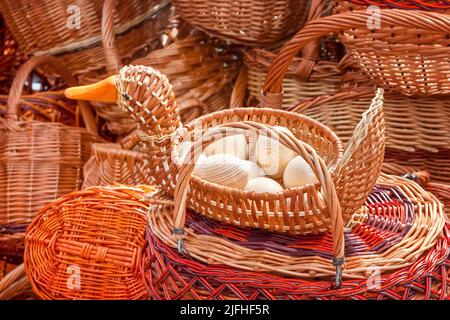 Korbkorb in Form einer Ente, gefüllt mit Holzeiern aus der Nähe. Handwerk im Osterstil Stockfoto