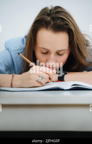 Müde Geschäftsfrau in blauem Hemd schlief ein, während sie in einem Tagebuch schrieb Stockfoto