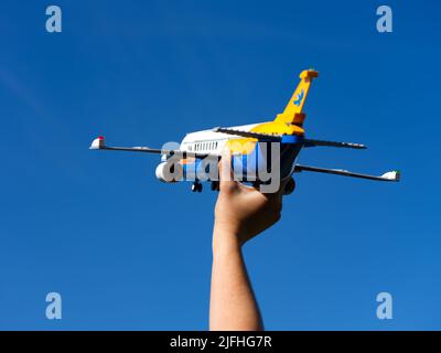Tambow, Russische Föderation - 30. Juni 2022 Eine Person hält ein Lego-Passagierflugzeug gegen den blauen Himmel Stockfoto