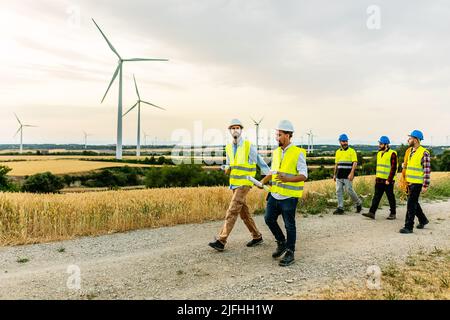 Techniker und Ingenieure, die auf einem Feldweg in einem Windpark unterwegs sind Stockfoto