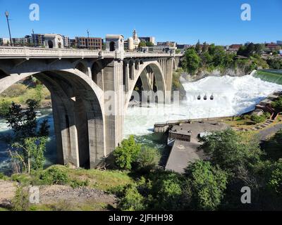 Sintflutartige Strömung über den Lower Spokane Falls unter der Monroe Street Bridge im Stadtzentrum von Spokane nach heftigen Regenfällen am hellen, sonnigen Sommermorgen. Stockfoto