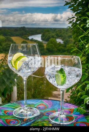 Zwei große und kleine Gin-Gläser mit Eiswürfeln und Limettenscheibe mit Blick auf die Brüstung von Richmond Hill und die Themse Stockfoto