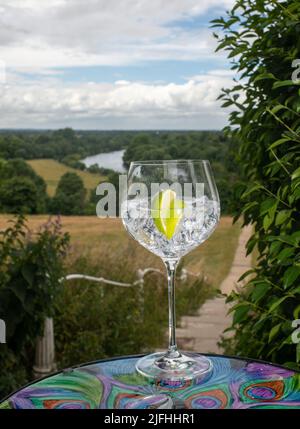 Gin-Glas mit Eiswürfeln und einer Scheibe Limette mit Blick auf die Brüstung von Richmond Hill zur Themse Stockfoto
