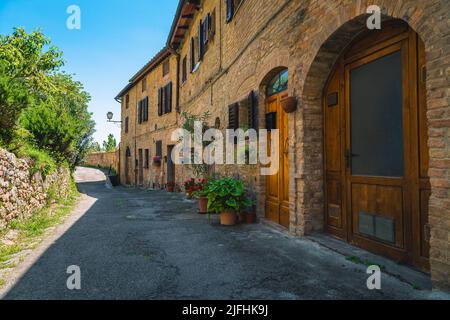 Rustikale toskanische Backsteinhäuser und gemütliche Eingänge mit bunten Blumen dekoriert. Fantastischer Blick auf die Straße in San Gimignano, Toskana, Italien, Europa Stockfoto