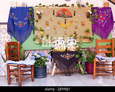 Typisch andalusischer Patio mit Gea-Stühlen, Tisch mit Misteln aus Manila, Ventilatoren und Wasserkrug und Töpfen an den Wänden. Typische Party im c Stockfoto