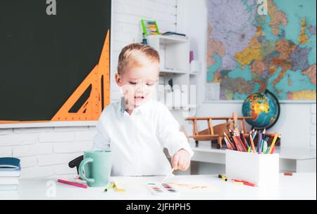 Bildungsprozess. Hausstudie. Lern- und Bildungskonzept. Nach dem Schulunterricht. Nettes Kind 3 Jahre alt im Klassenzimmer in der Nähe von Tafel Schreibtisch Stockfoto