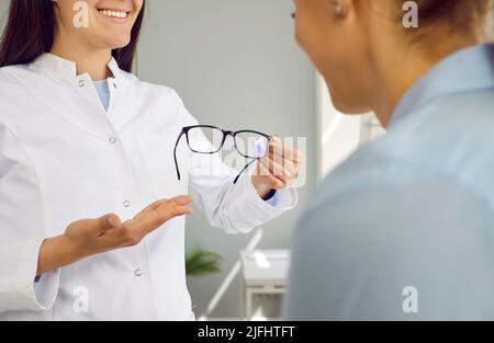 Freundliche Optikerin arbeitet mit der Patientin zusammen und zeigt ihre neue Brille zum Testen und Ausprobieren. Stockfoto