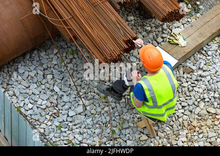 Arbeiter, die Markierungen auf Metallverstärkungsstäben machen Stockfoto