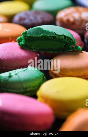 Traditionelle französische Desserts, mehrfarbiger Macaron mit Fruchtgeschmack, Nahaufnahme, vertikaler Hintergrund im Vollformat Stockfoto