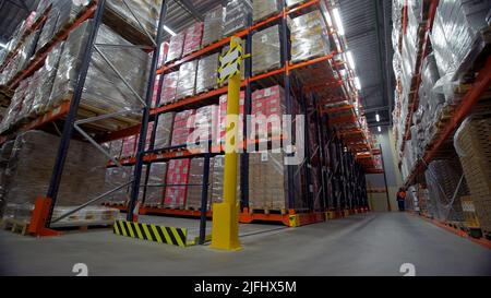 Postlager.Kreativ. Ein Lager, in dem Menschen verschiedene große Pakete verteilen und verteilen und den Prozess kontrollieren. Stockfoto