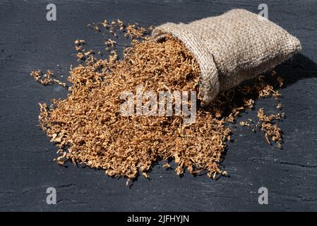 Hochwertiger Tabak zum Rauchen in Sackleinen auf dunklem Hintergrund. Stockfoto