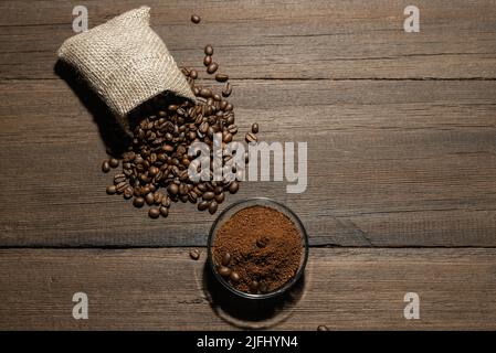 Körner von frisch geröstetem Kaffee und gemahlenem Kaffee auf einem hölzernen Hintergrund. Die Textur von Kaffeebohnen. Stockfoto
