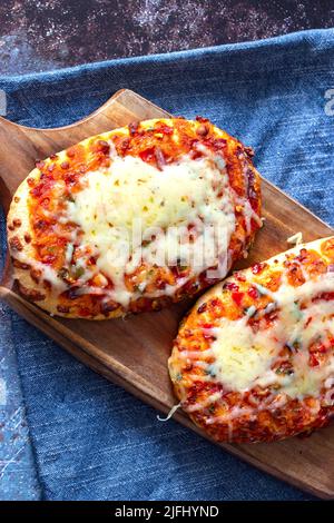 Gemüsepizza mit geschmolzenem Käse, gekocht auf einem Holzbrett. Mit einem Geschirrtuch auf einem grunge Hintergrund. Stockfoto