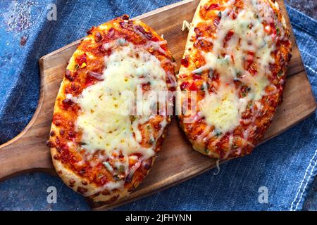 Gemüsepizza mit geschmolzenem Käse, gekocht auf einem Holzbrett. Mit einem Geschirrtuch auf einem grunge Hintergrund. Stockfoto