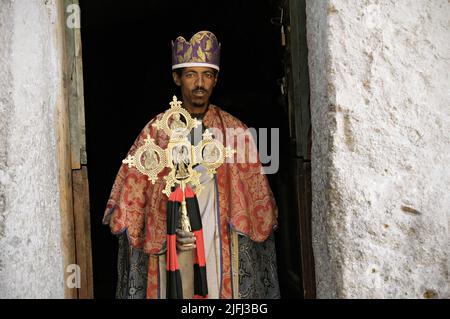 Priester hält ein äthiopisches Kreuz vor der Tür der Kirche Ashetan Maryam, Lalibela, Amhara Region, Äthiopien Stockfoto