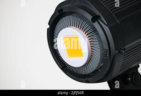 Gelbes LED-Modul im Fotoreflektor mit Aluminium-Kühlrippen auf weißem Hintergrund. Schwarzes elektrisches Hochleistungslicht von Halbleiterdioden. Stockfoto